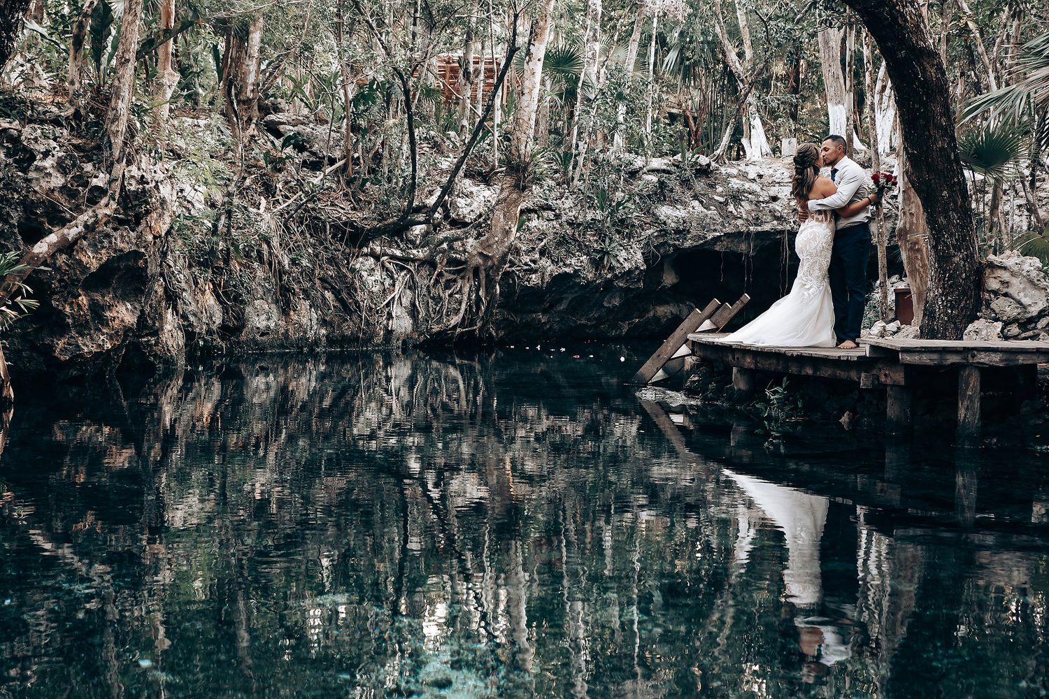 Crystal clear waters reflect the romantic scene in a naturally lit underground cave wedding.