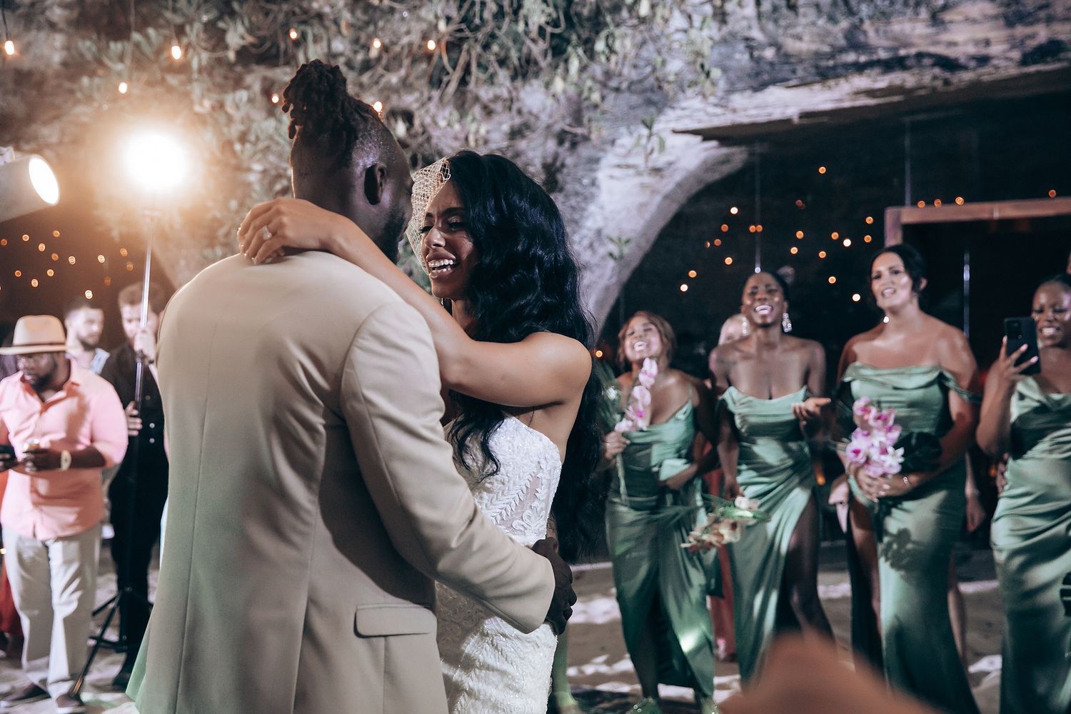 Wedding guests celebrate on a dimly lit dance floor with sparkling lights creating a magical atmosphere.