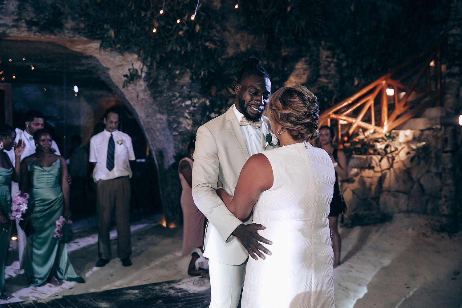 Intimate first dance moment at an evening wedding reception with stone walls and ambient lighting.