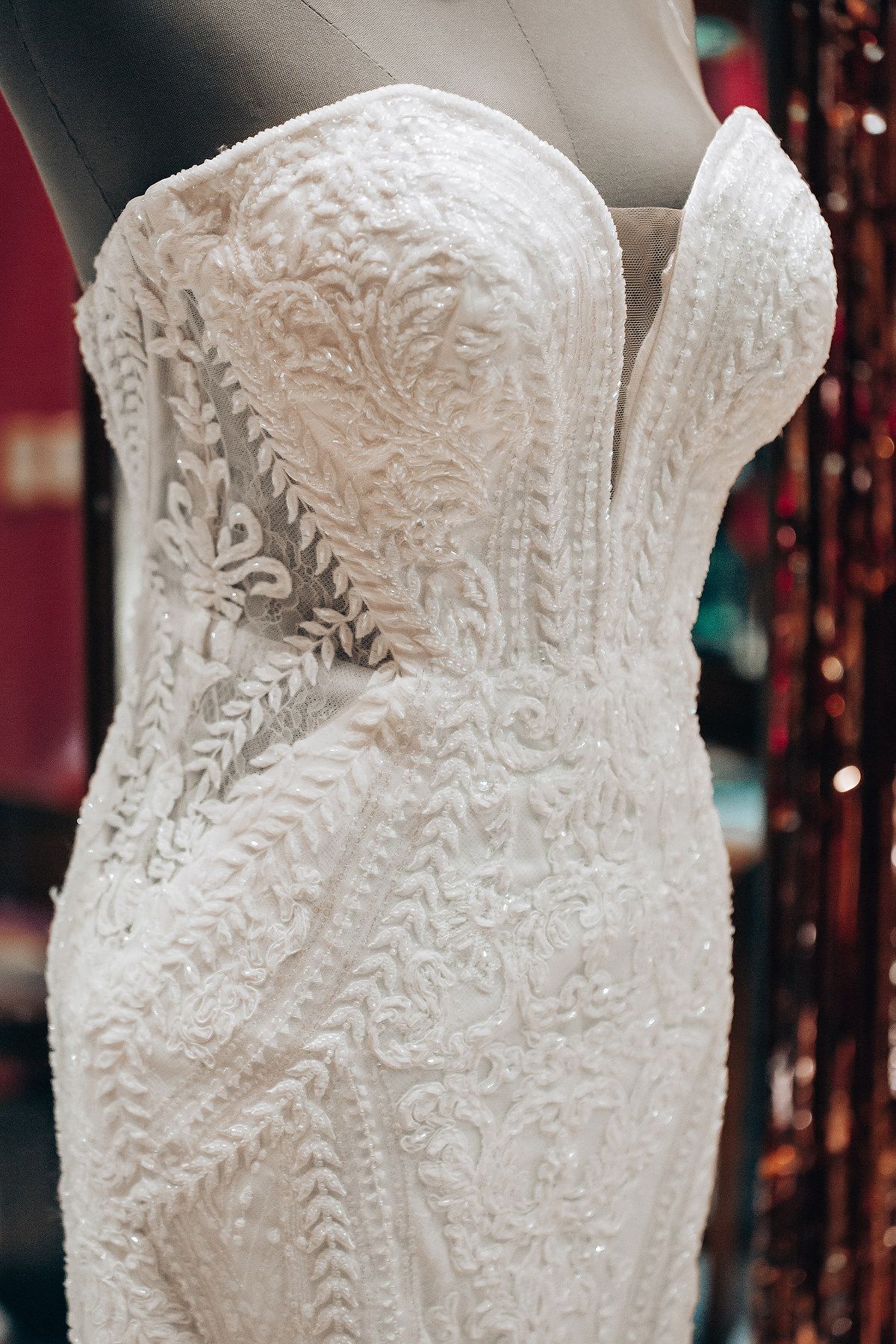 Close-up details of an ornate white lace wedding dress bodice with intricate embroidered patterns.