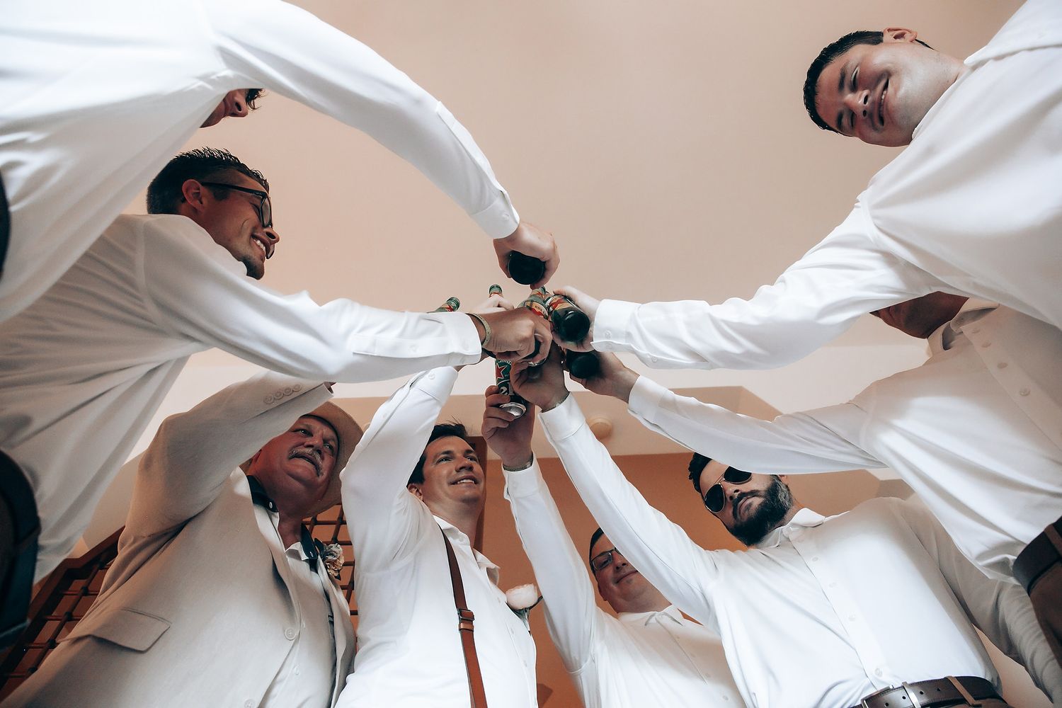 Groomsmen in white shirts jumping and celebrating together in a fun group photo.