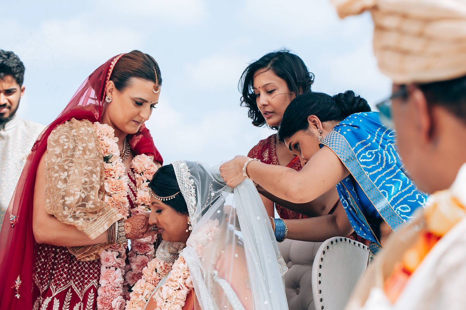 Wedding ceremony participants celebrate during a beachside event with colorful traditional attire.