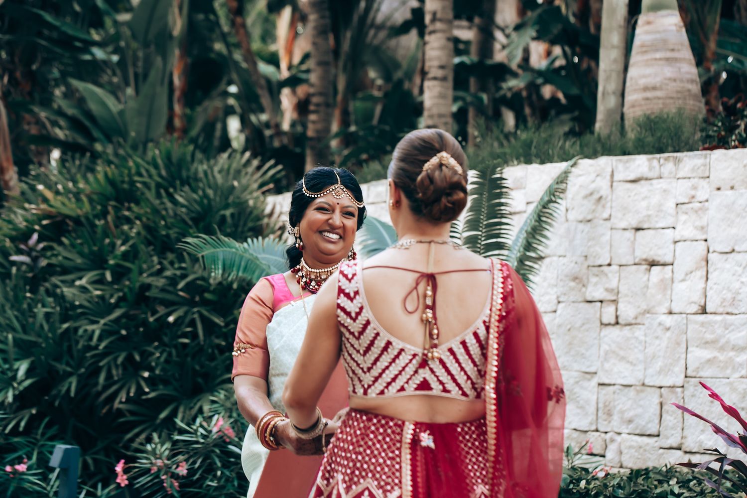 Wedding celebration in a tropical garden setting with palm trees and stone walls.