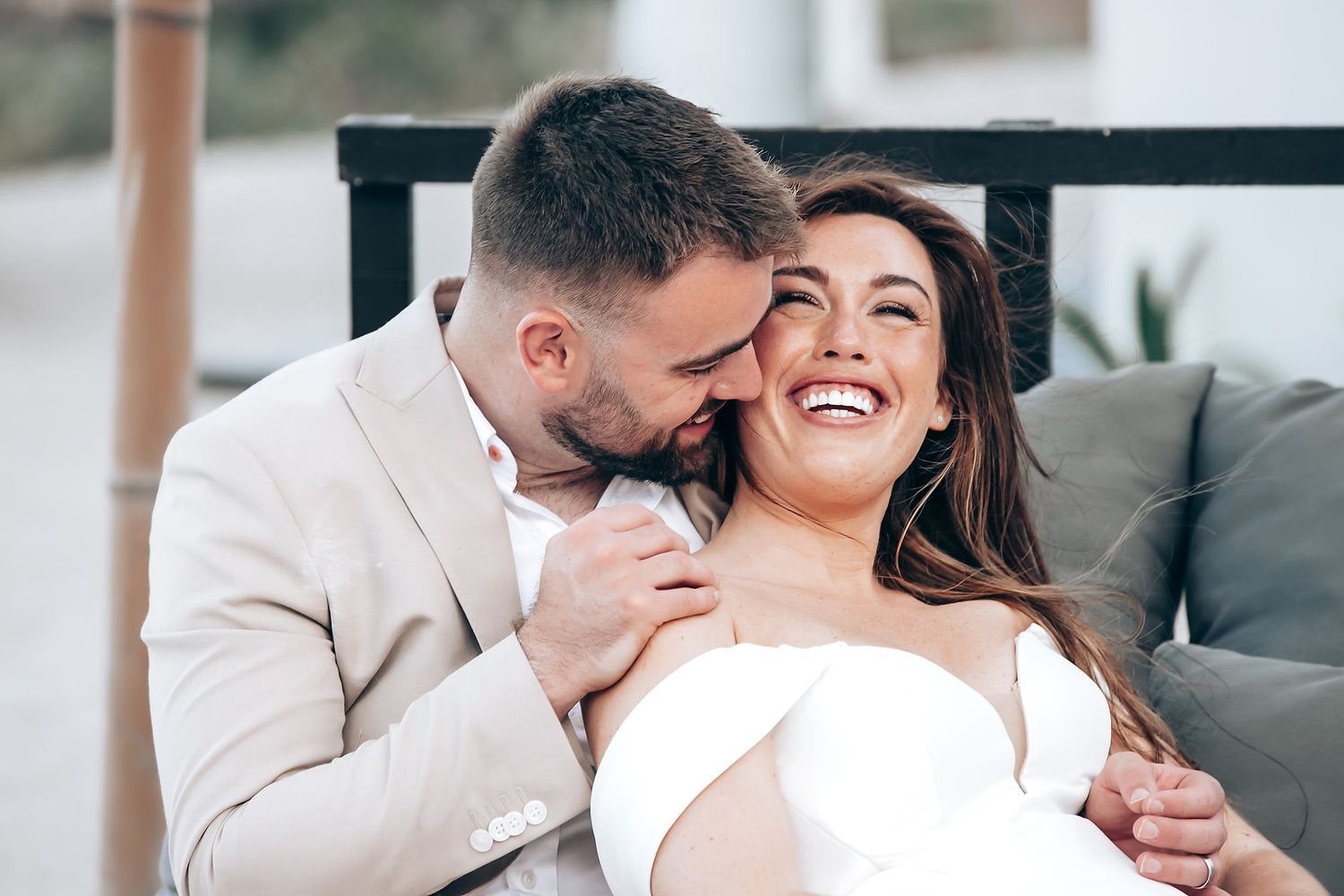 Happy couple embracing and laughing together on a comfortable grey couch.