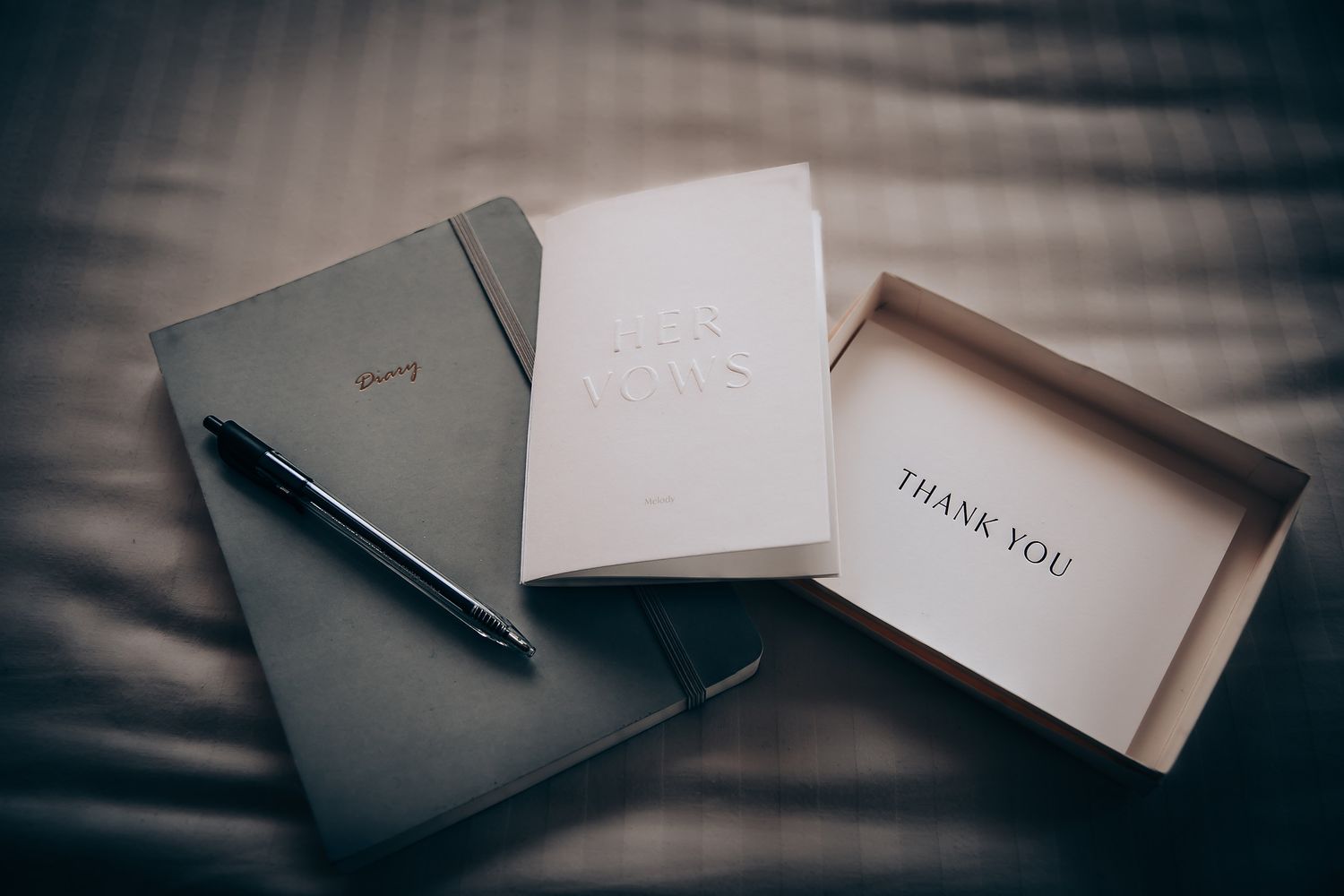 Minimalist composition of thank you cards and writing materials on a dark surface.
