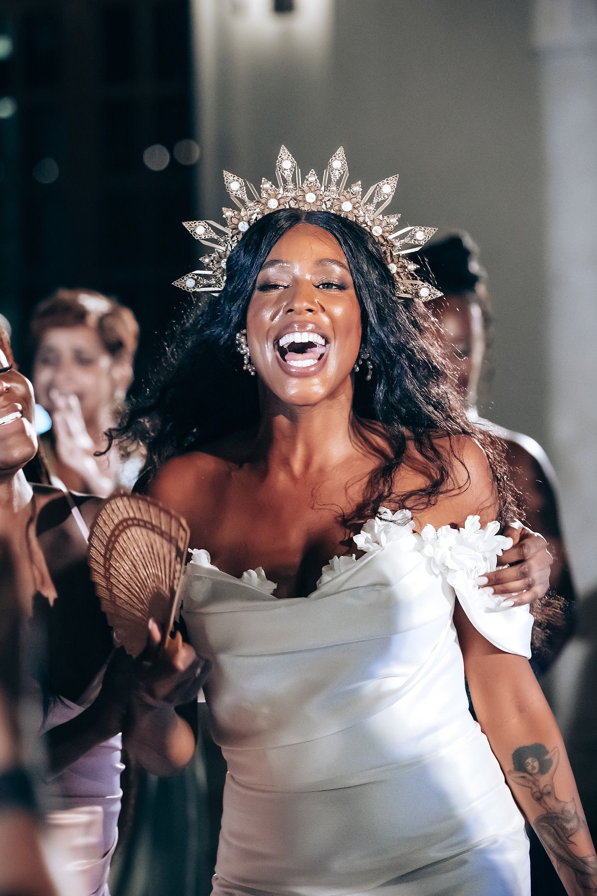 Joyful wedding reception moment with crystal crown and white dress against dark background.