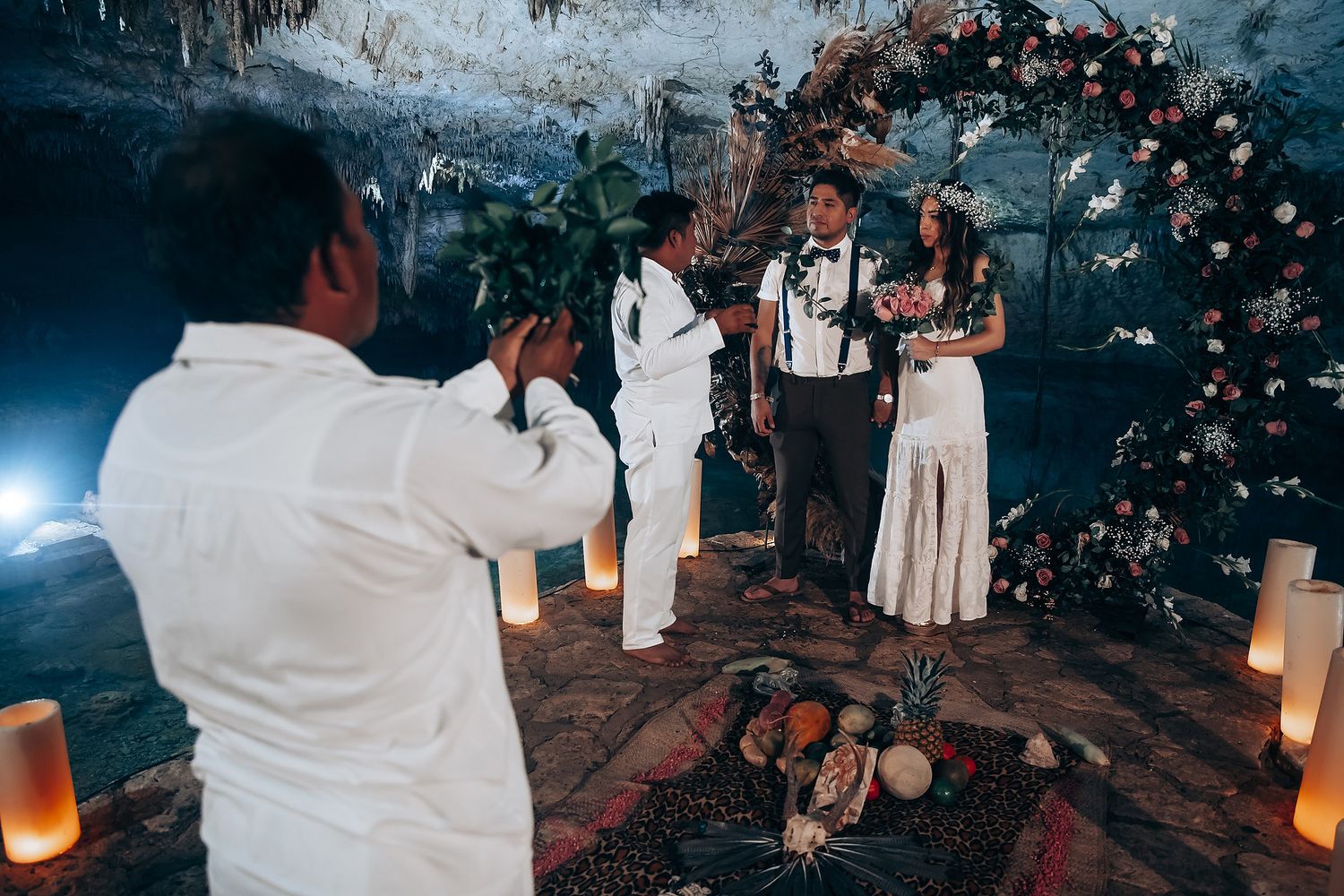 Wedding guests gather in an outdoor evening celebration illuminated by lanterns and floral decorations.