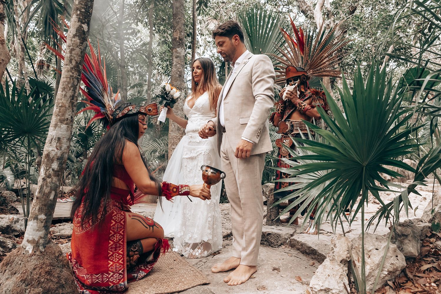 A romantic outdoor wedding ceremony with a couple exchanging vows under palm trees and natural foliage.