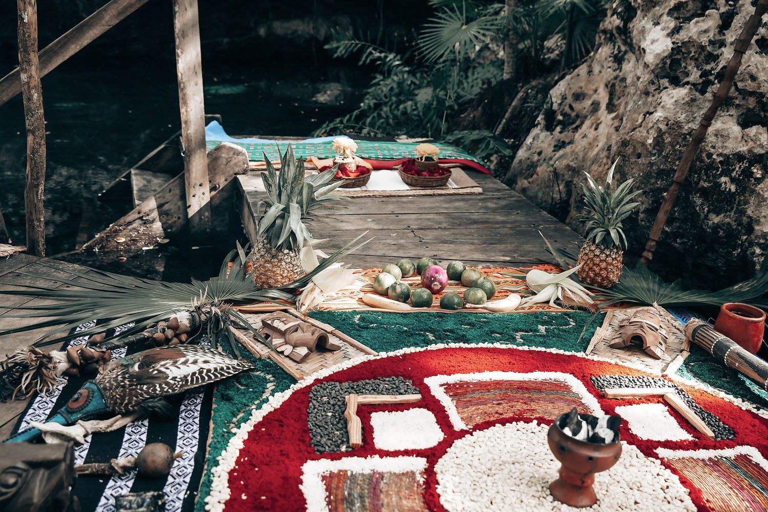 A tropical outdoor dining area with a wooden deck, potted plants, and decorative elements.