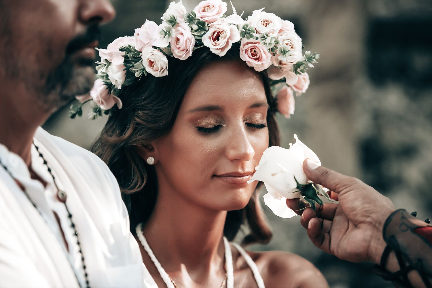 A woman wearing a floral crown stands with a man in a natural, wooded environment.