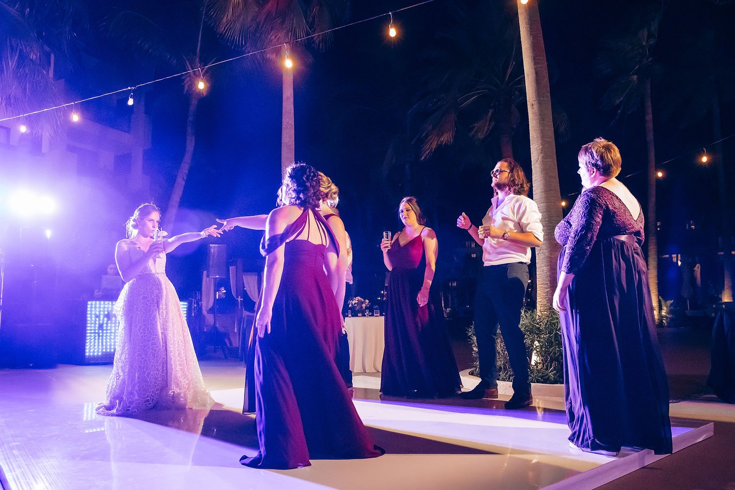 A bride and groom dance together at their wedding reception with other guests in the background.