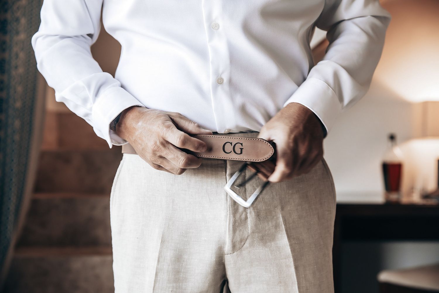 A person wearing a white shirt and tie adjusts their belt.