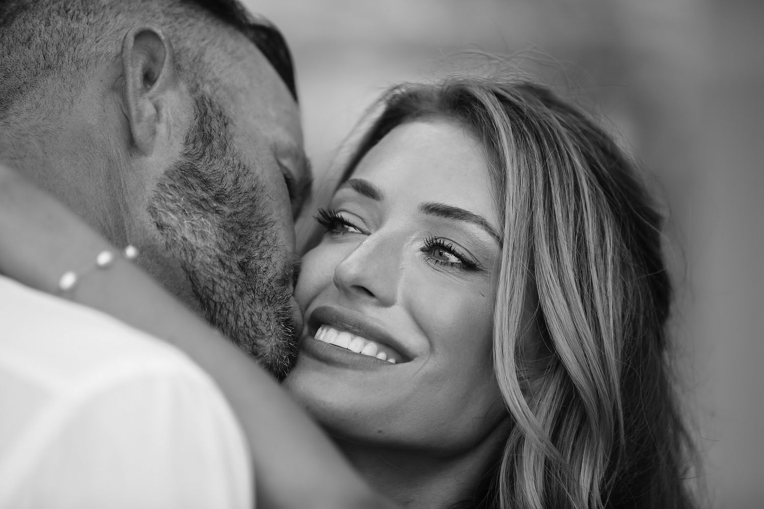 A black and white portrait of a smiling couple embracing.