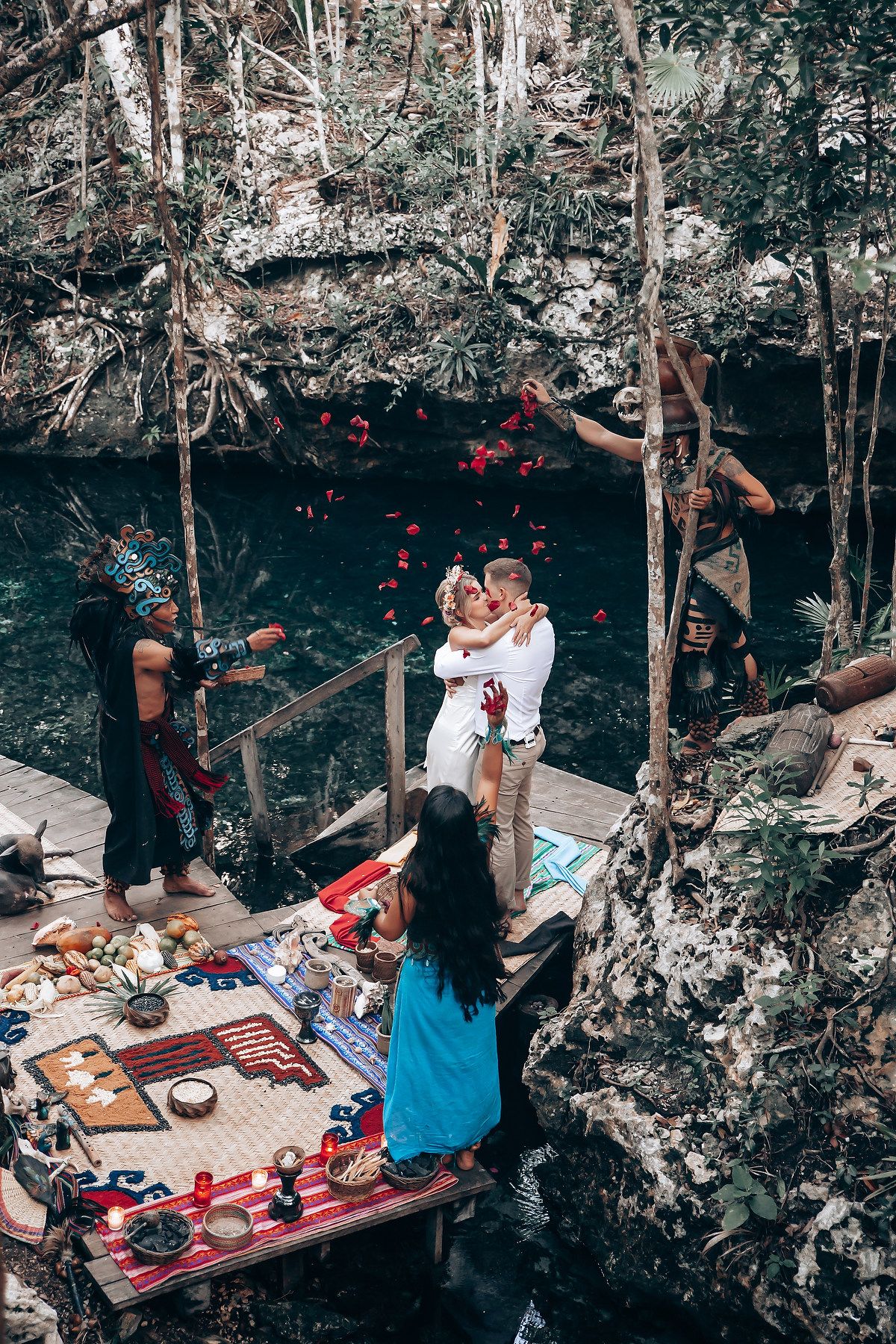 A rustic outdoor wedding ceremony space with red decorations and natural rock formations.