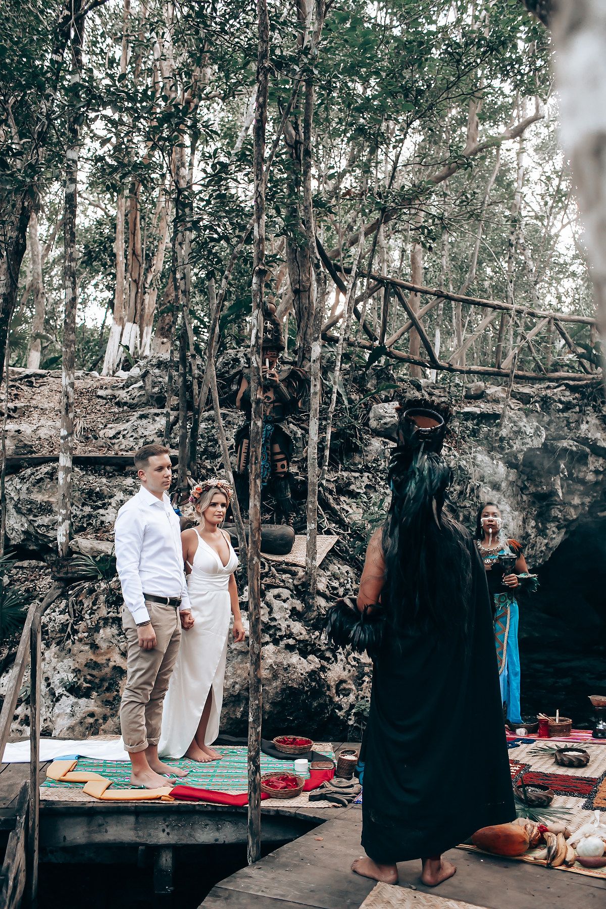 People gathered in a rustic outdoor setting with stone walls and trees.