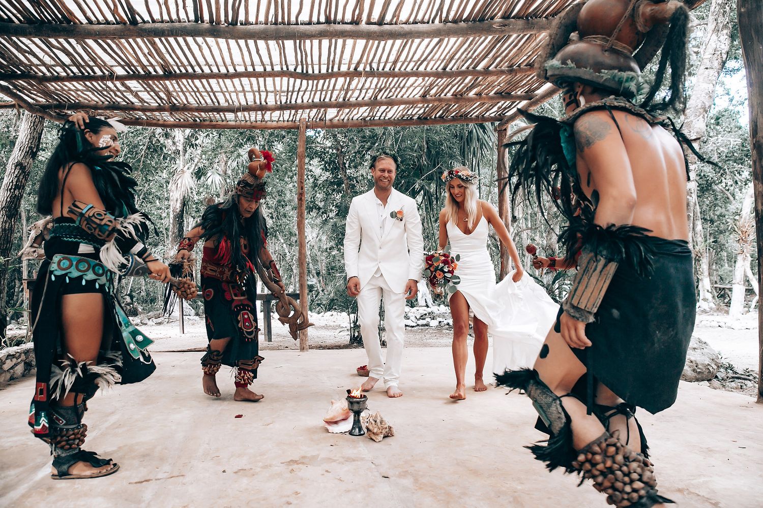 Traditional Mayan ceremony with dancers in ceremonial dress and spectators in white clothing.