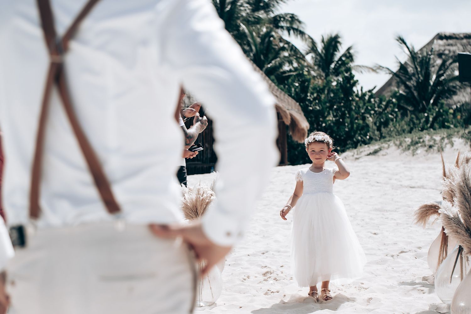 Wedding guests walking along a tropical beach path with white decorations.
