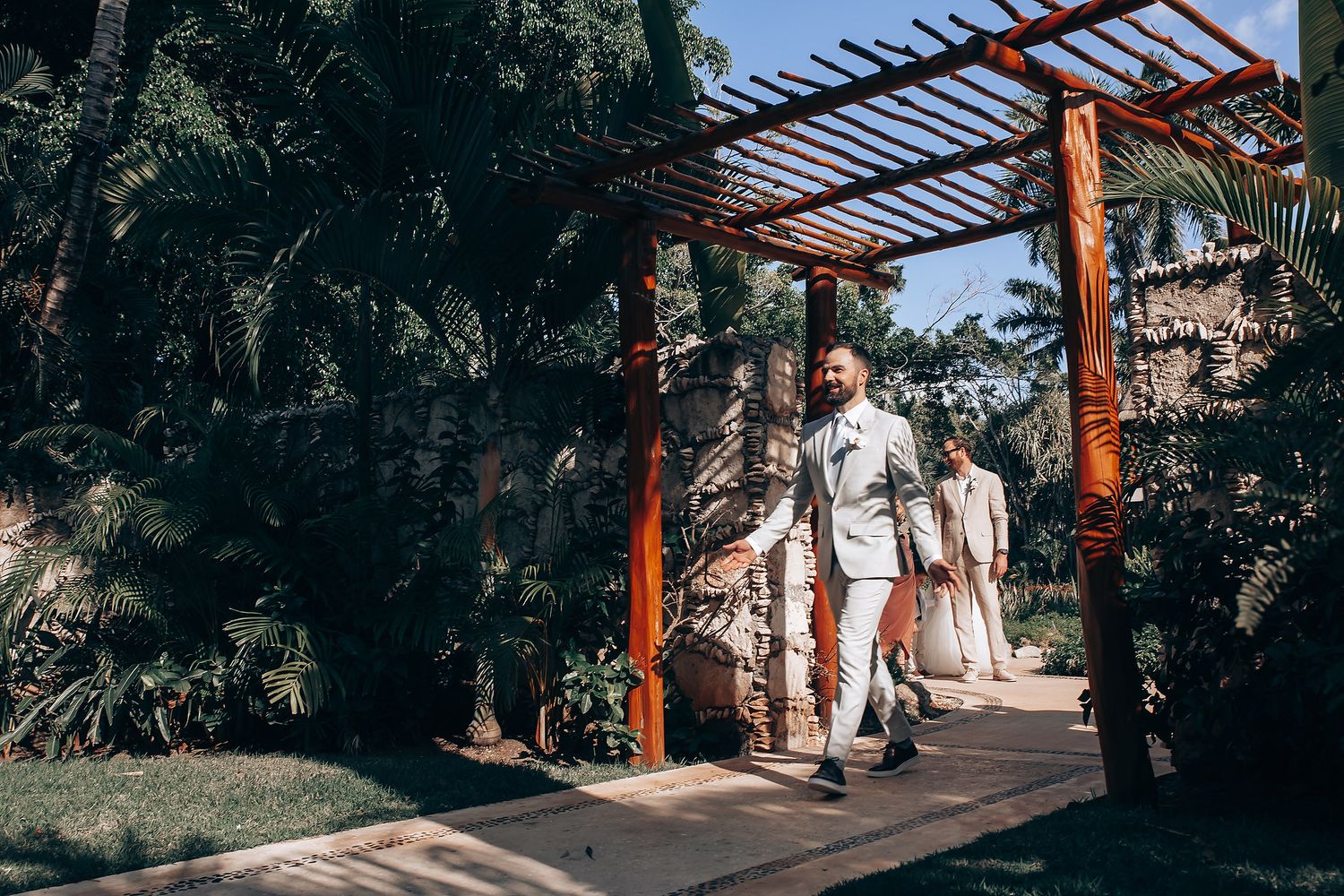 Outdoor wedding venue with wooden pergola and tropical landscaping.