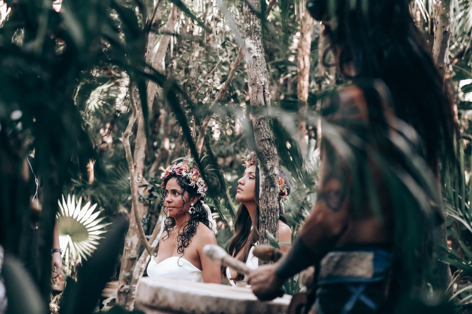 Outdoor gathering in a tropical garden setting with white-clad figures among the greenery.