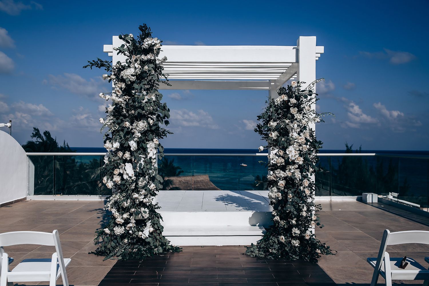 Panoramic view of a white wedding arch against a bright blue sky.