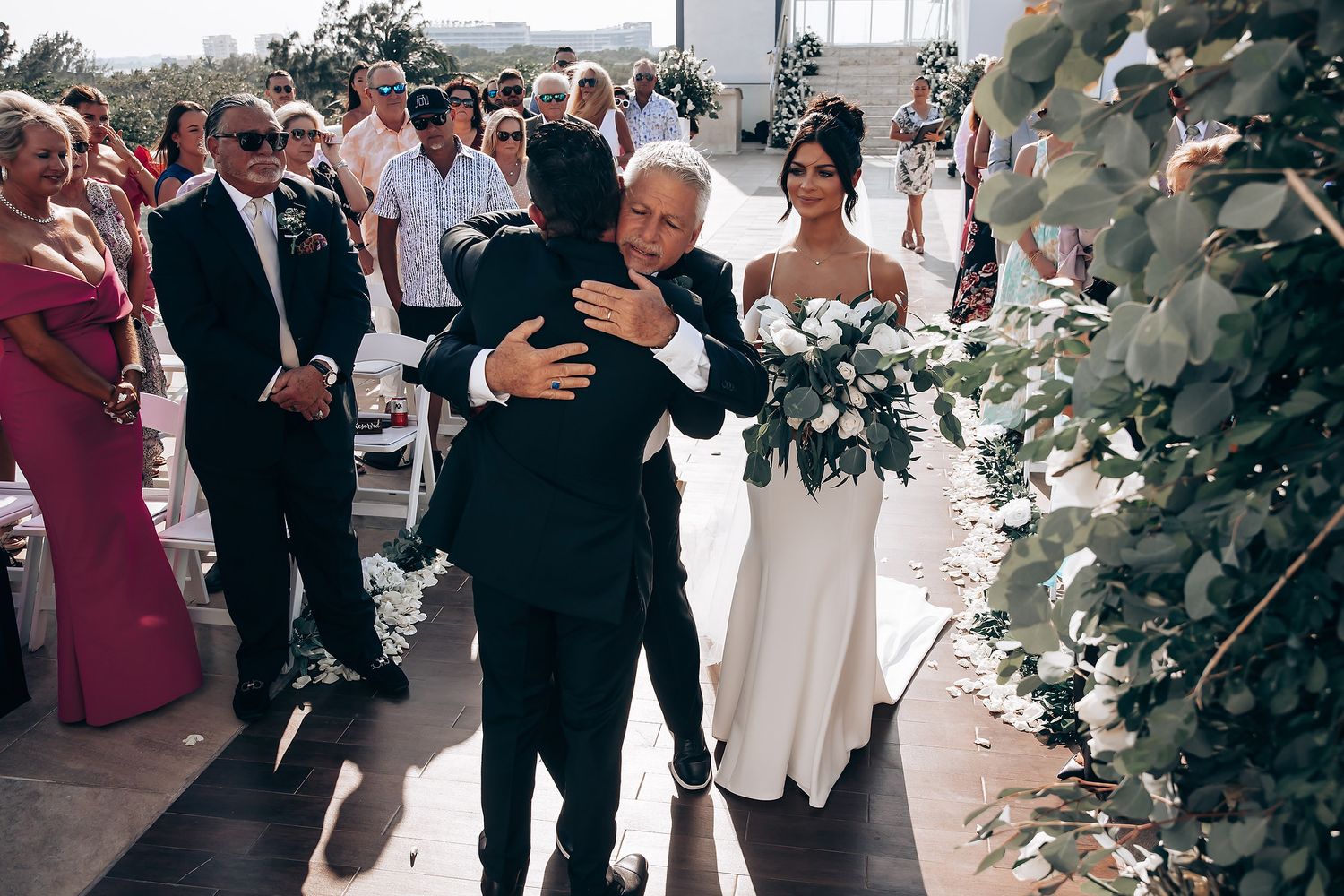 Wedding ceremony setup with white floral arrangements and guests seated outdoors.