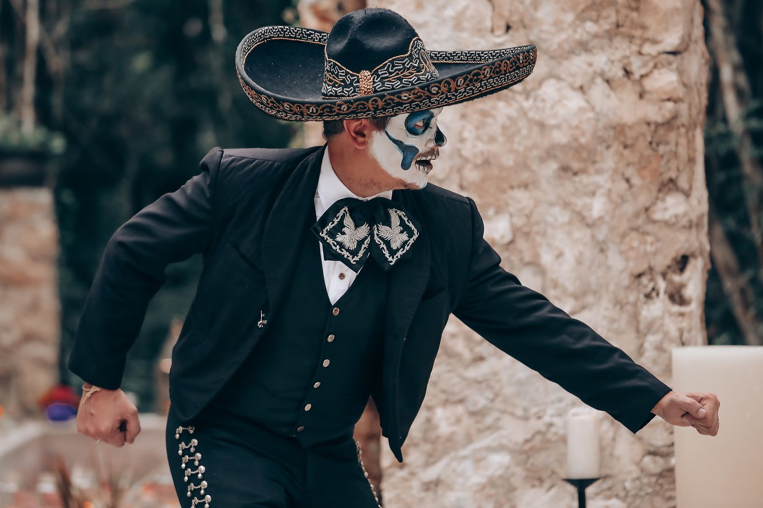 A performer in vintage black attire strikes a dramatic pose during an outdoor forest dance.