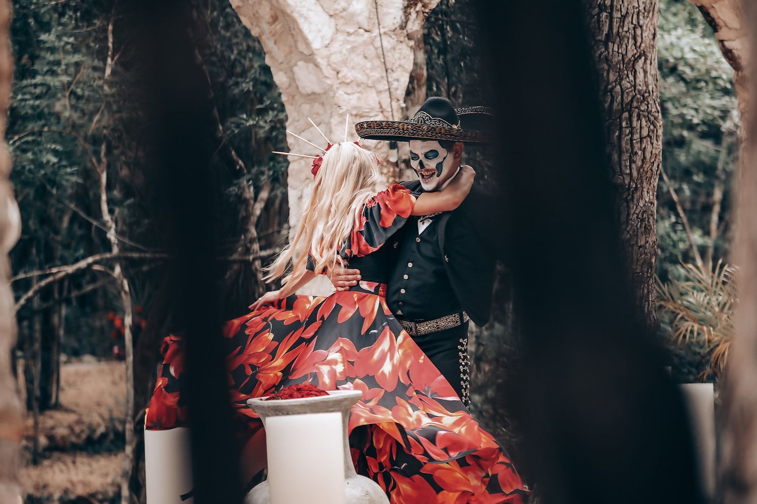 Dancers in red and black attire perform an expressive routine among trees in a forest setting.