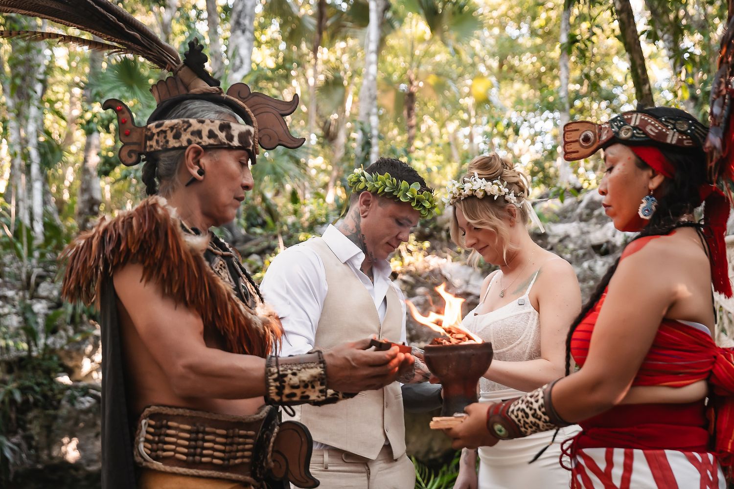 Couple exchanging vows in a traditional Mayan wedding ceremony with costumed officiants in a lush jungle setting.