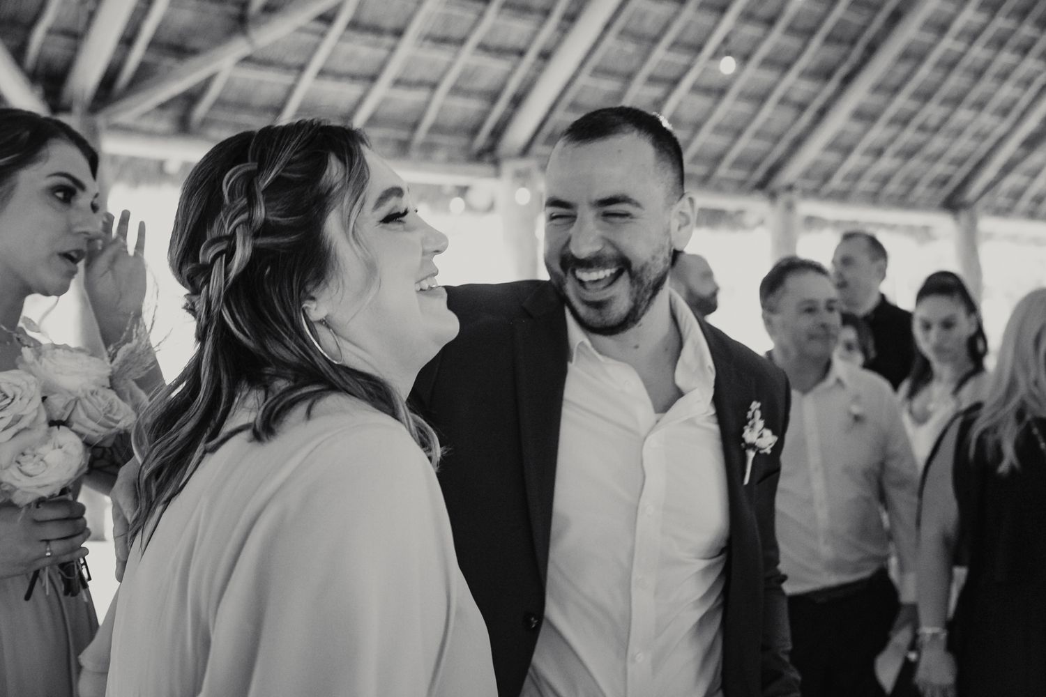 Bride and groom share a joyful laugh together during their wedding reception in black and white.