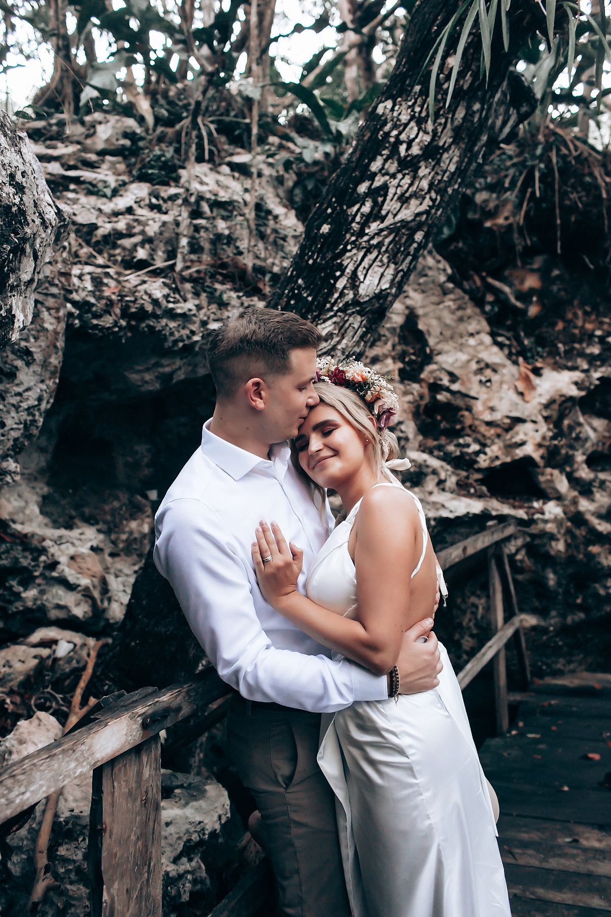 A tender embrace captured against a backdrop of rocky cliffs and tropical forest.
