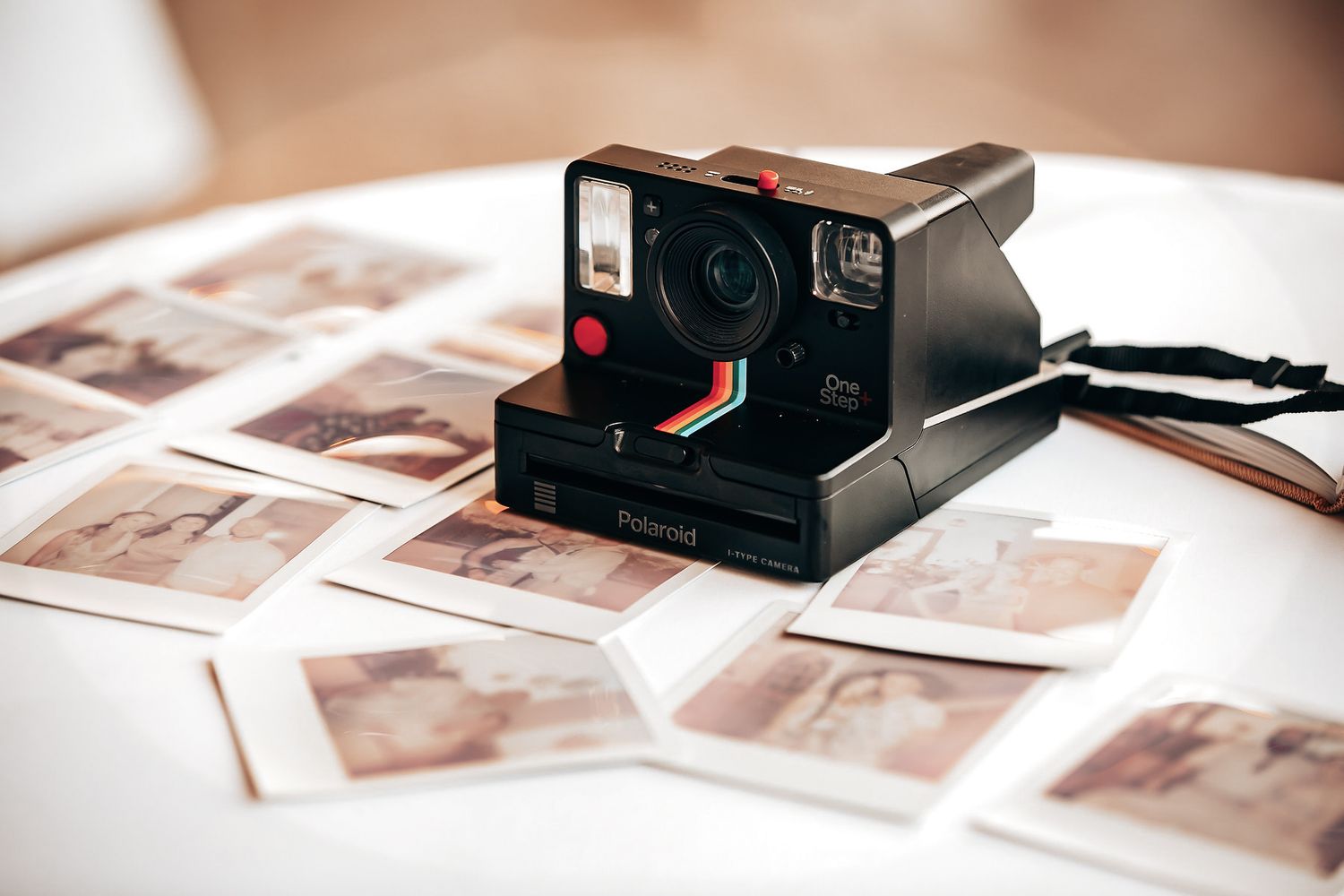 An old-fashioned Polaroid camera with several developed photos on a table.