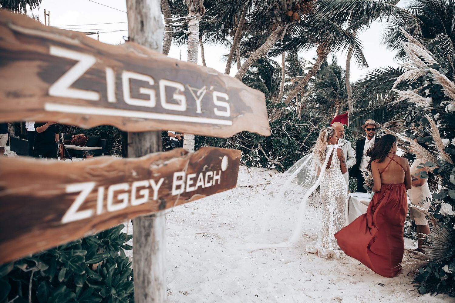 Beach wedding venue with palm trees and Ziggy's Beach signage visible in tropical setting.