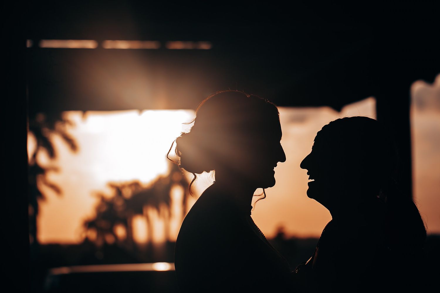 Romantic silhouette of a couple against a warm sunset backdrop.