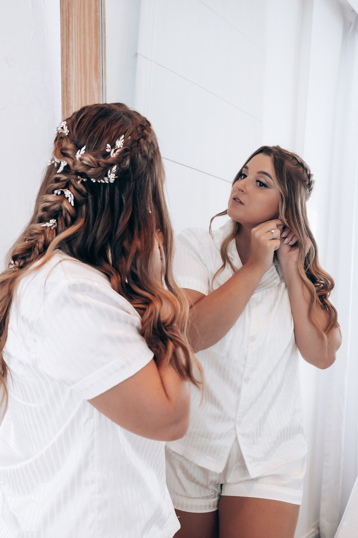 A reflection in a mirror shows elegant bridal hair styling with delicate floral accessories.