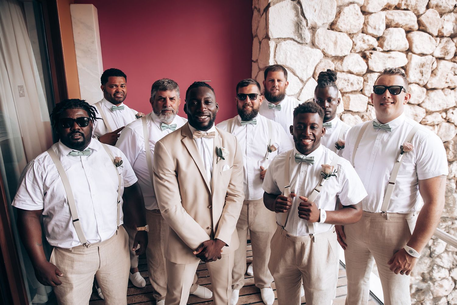 Groomsmen in light beige suits posing together for wedding photos.