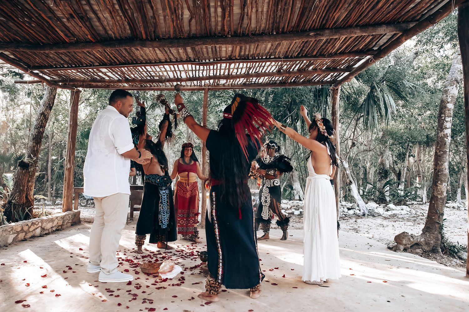 Outdoor spiritual gathering under wooden canopy with traditional decorations.