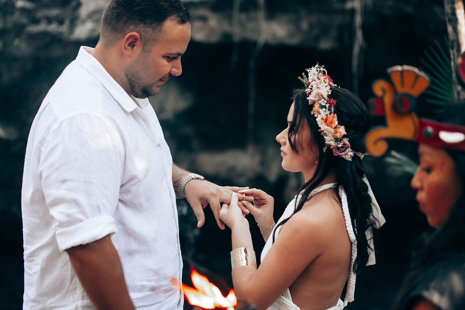 Traditional ceremony taking place outdoors with participants seated on decorated ground.