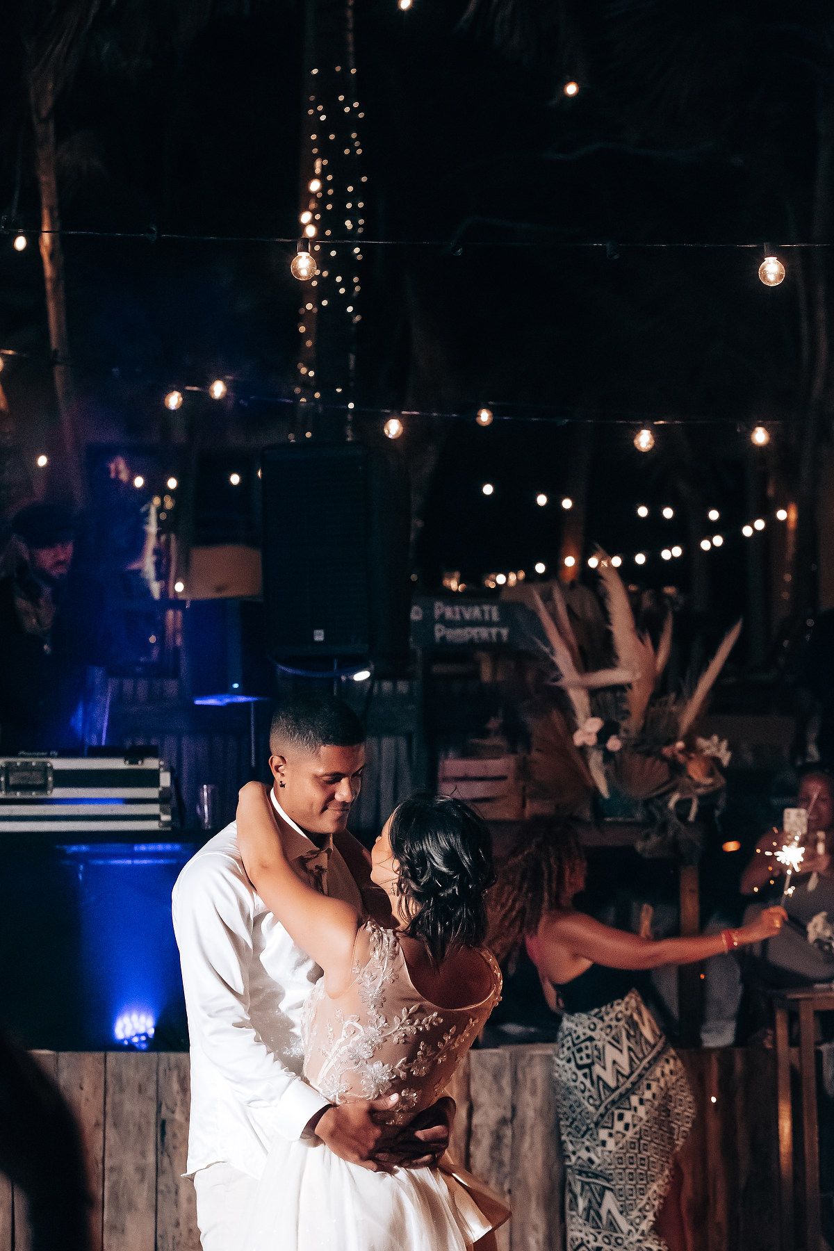 Evening wedding reception with string lights creating a romantic ambiance outdoors.