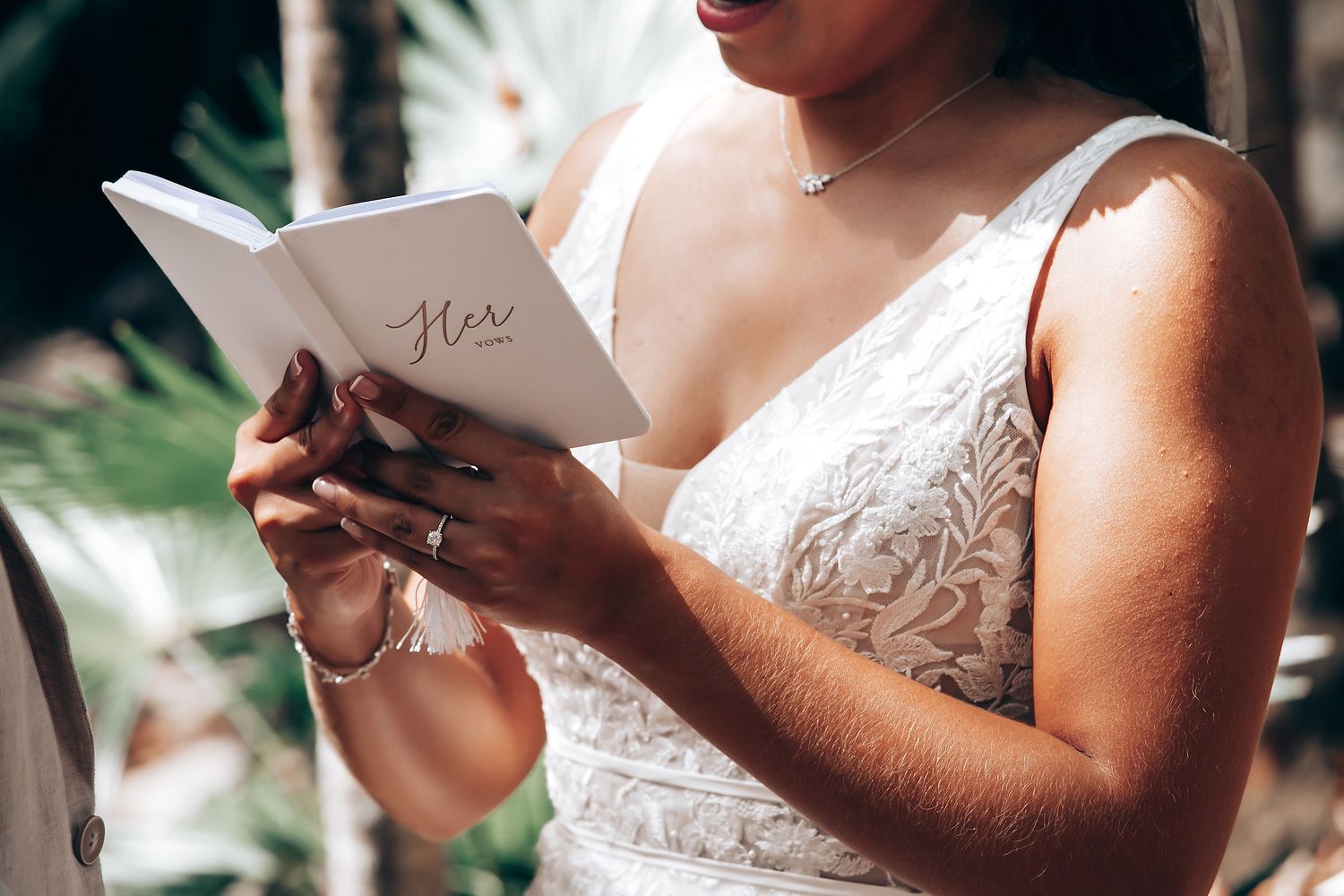 Close-up of hands holding wedding vows written on paper during an outdoor ceremony.
