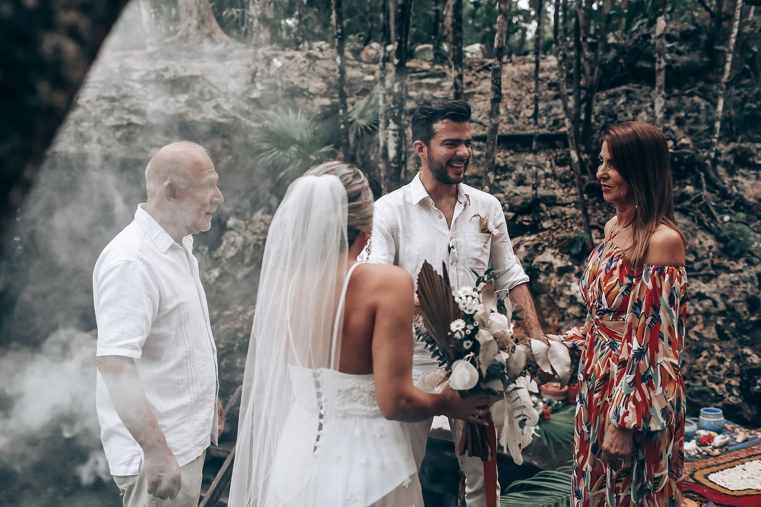 A wedding ceremony in a forest clearing with guests and traditional Indigenous elements.