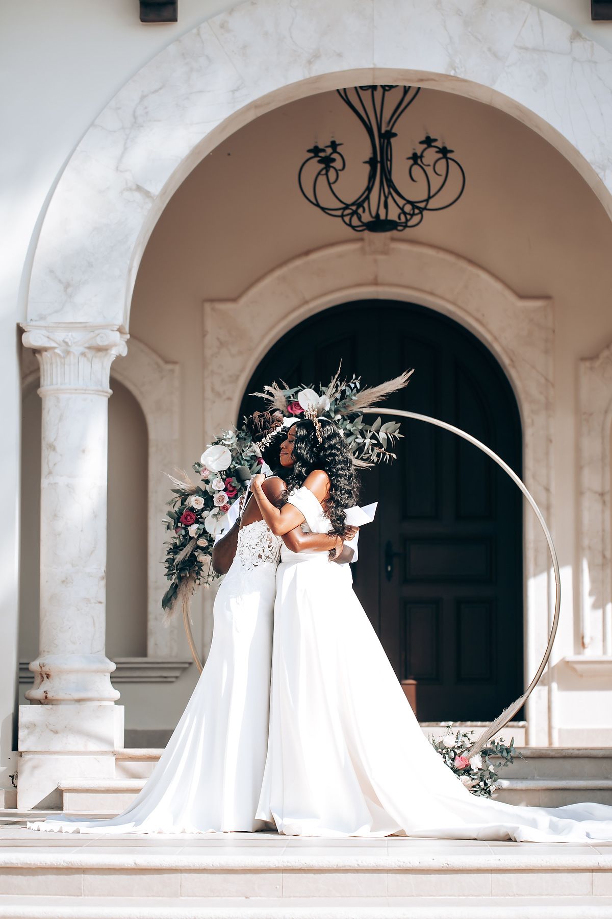 Elegant bridal photo shoot under white marble arches decorated with floral arrangements.