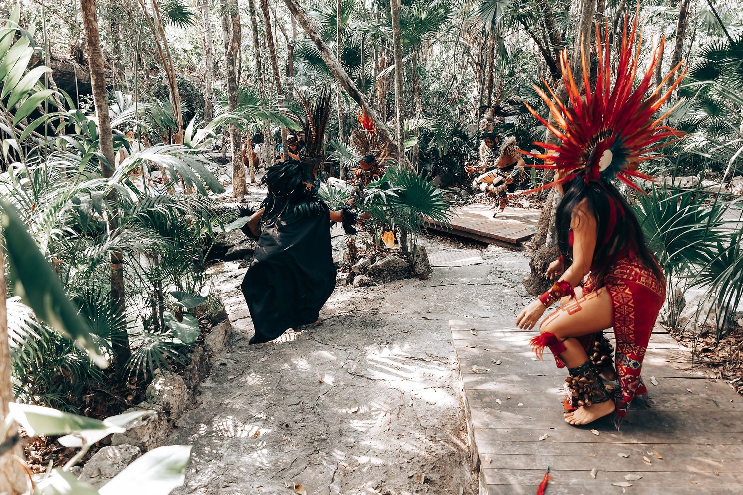 Traditional Mayan blessing ceremony with red feathered headdress in jungle environment.
