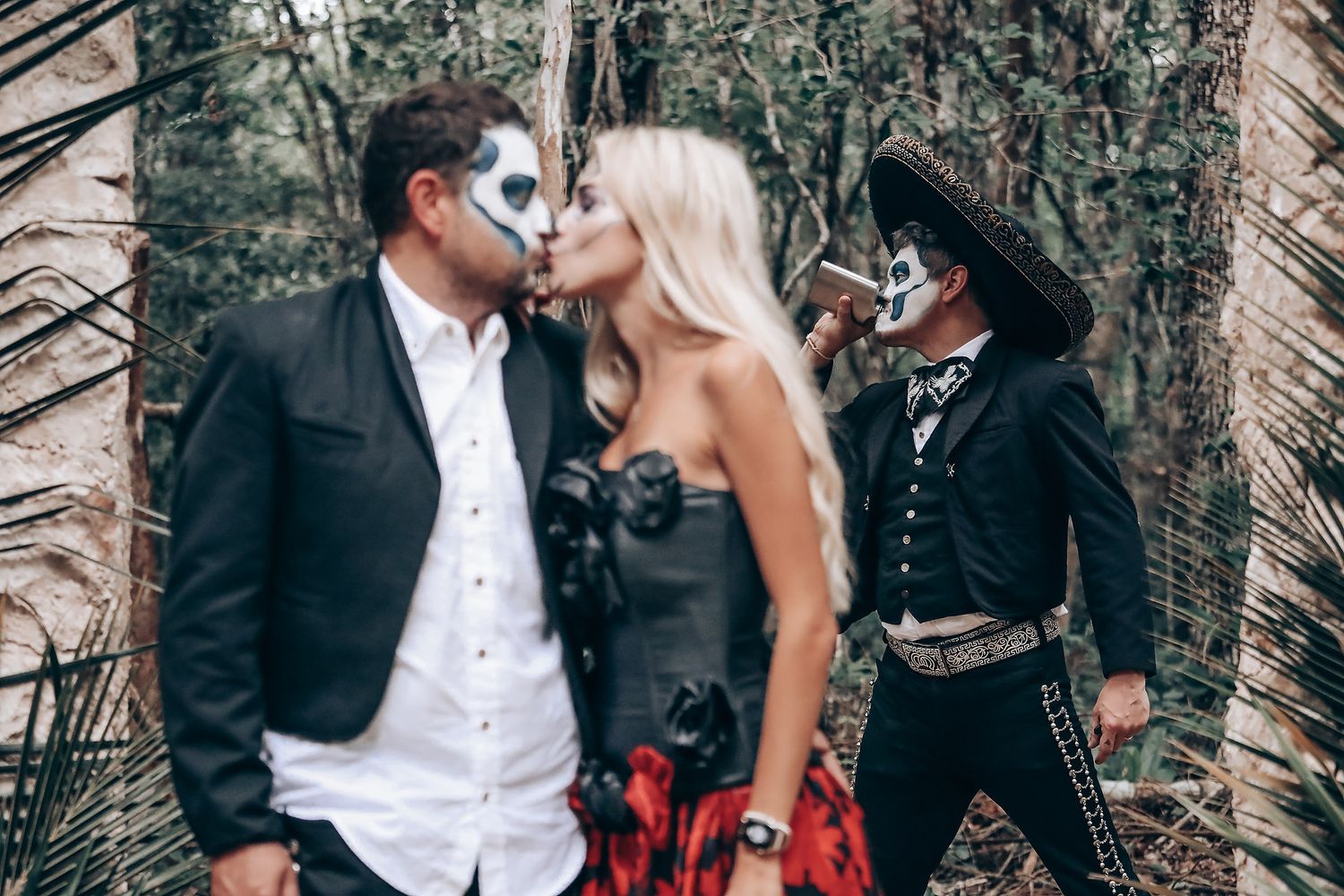 Romantic gothic wedding scene with formal attire and dark themed decorations in forest setting.