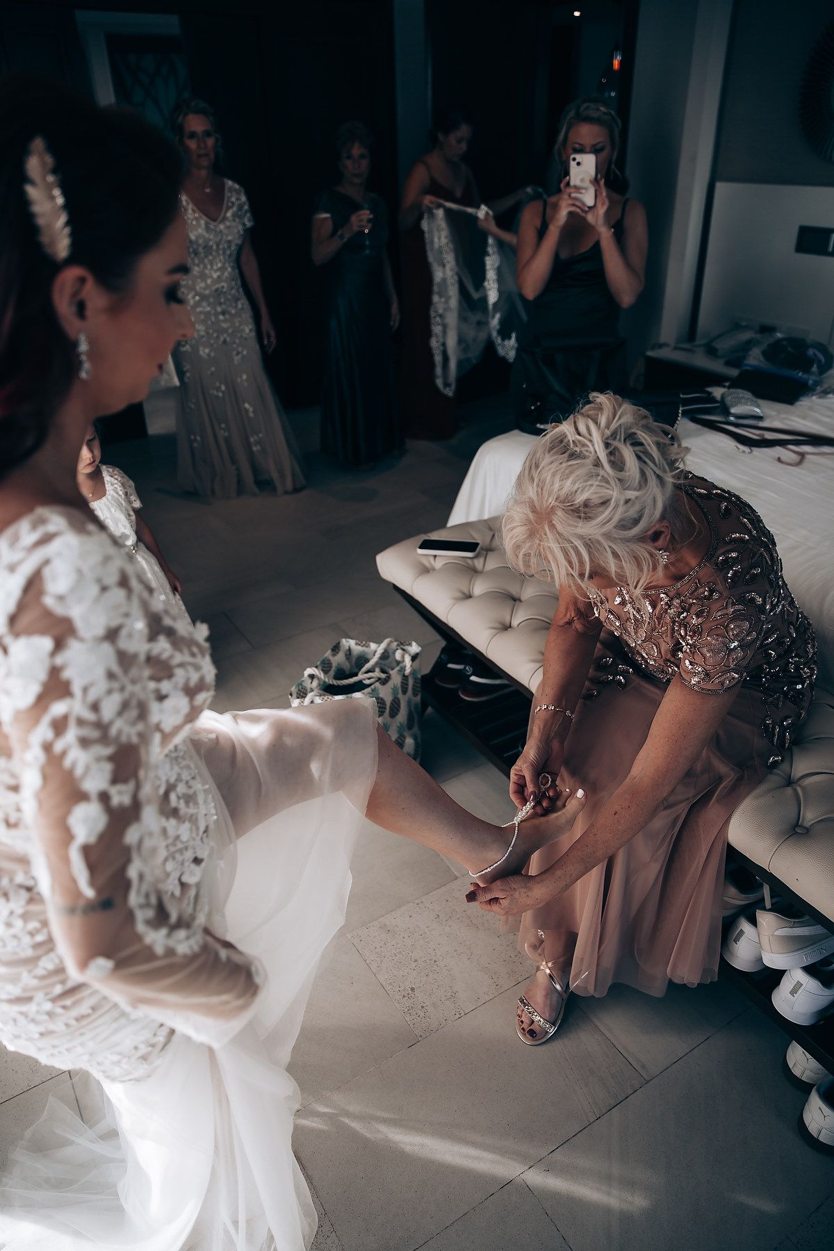 Wedding preparation moments showing details of white lace dresses and gowns in a dimly lit room.