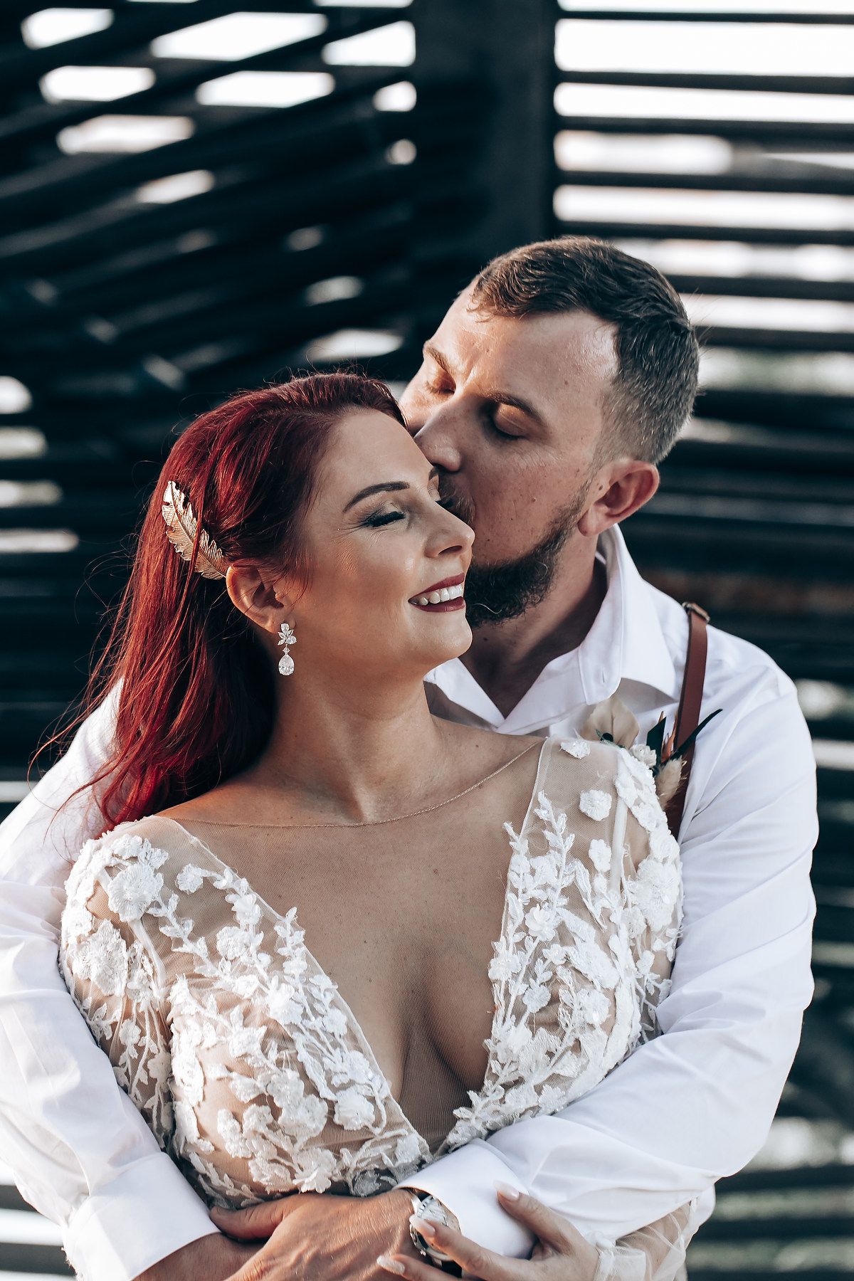 Romantic couple poses in white attire under industrial lighting.