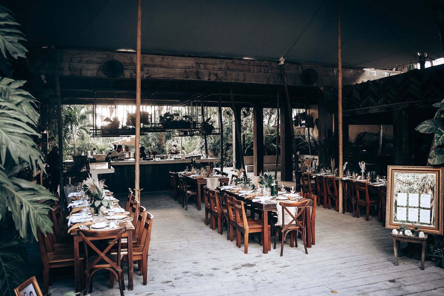 Rustic wooden restaurant interior with hanging pendant lights and tropical decor creating an intimate dining atmosphere.