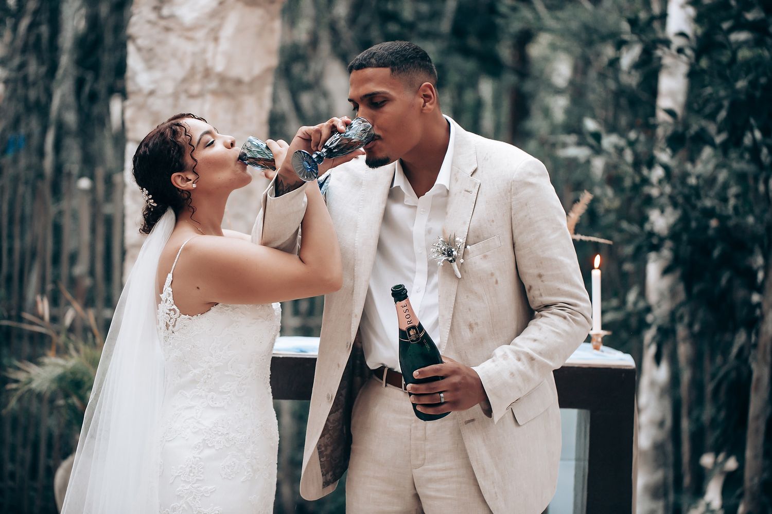 Wedding couple shares drinks during their outdoor forest celebration.