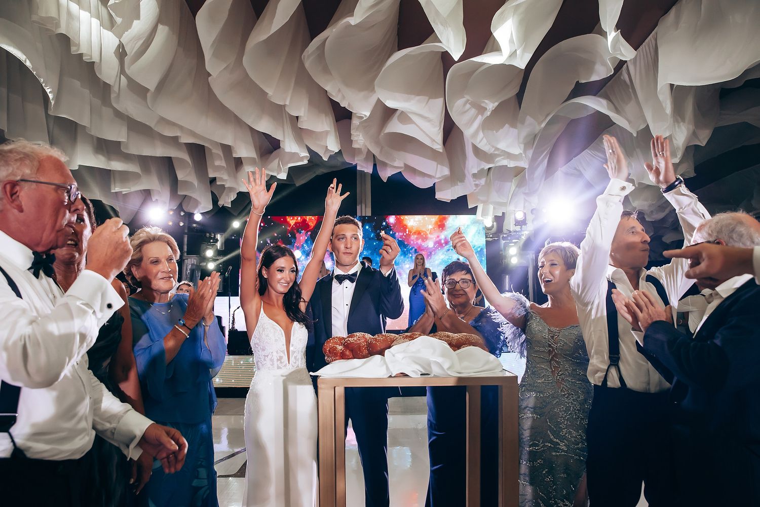 Wedding celebration with white fabric ceiling decorations and dancing guests.