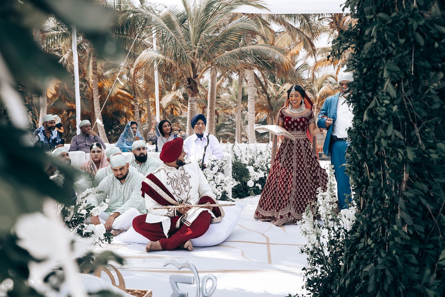 Beachside wedding ceremony with tropical palm trees and white decorations.