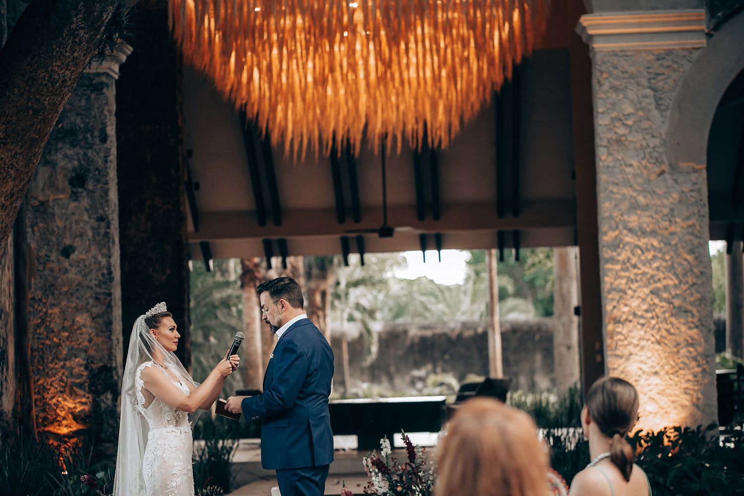 Wedding celebration in a rustic venue with warm lighting and stone pillars during a romantic first dance moment.